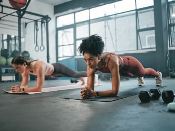 Entrenamiento de fuerza para corredores: dos corredoras entrenan sus músculos centrales haciendo planchas.