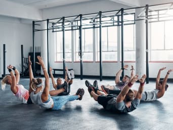 Strength exercises for runners: a fitness class doing a core workout in a gym.