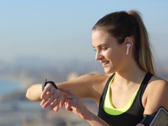 Programma di corsa per principianti: una donna controlla il battito durante l’allenamento di corsa con l’aiuto di un orologio sportivo. 