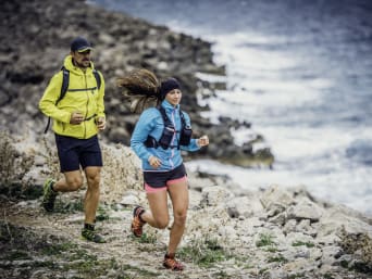 Trail running essentials: two runners wearing running clothes and carrying water bottles.