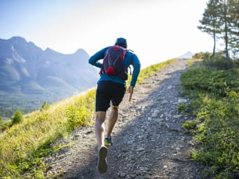 Equipamiento para trail running: un corredor corre por el monte con una mochila.