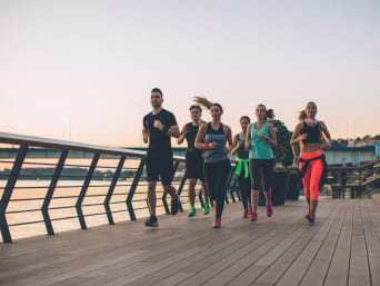 Laufplan für Anfänger: eine Gruppe Läufer joggt gemeinsam über eine Brücke.