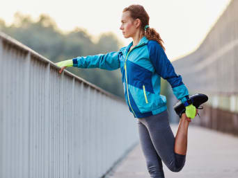 Rozciąganie po bieganiu, kobieta rozciąga mięśnie uda.
