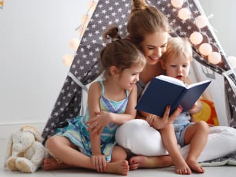Stimolare l’apprendimento della lettura nei bambini: una mamma legge un libro ai suoi figli.