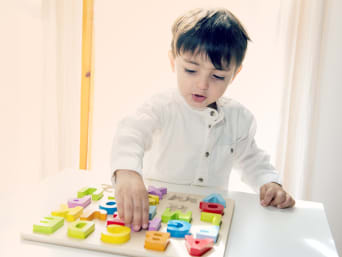 Alvast het lezen stimuleren: jongen speelt met houten letters.