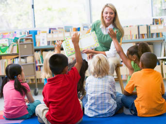 Mehrsprachigkeit bei Kindern: Erzieherin im Kindergarten zeigt ein mehrsprachiges Bilderbuch.