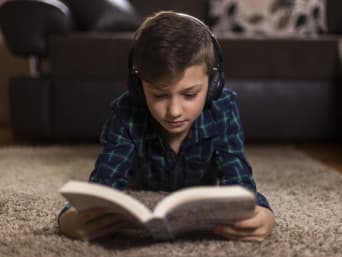 Jongen leest een boek met koptelefoon.