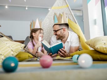 Kindern vorlesen: Ein Vater liest seiner Tochter eine Märchen-Geschichte vor. 
