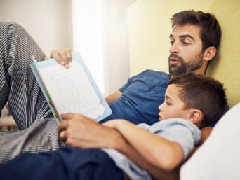 Ein Vater liest seinem Sohn aus einem Kinderbuch vor.