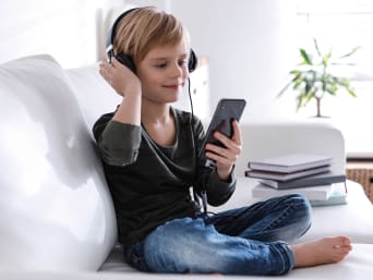 Kindveilige mobiele telefoons - jongen luistert naar muziek op zijn smartphone.