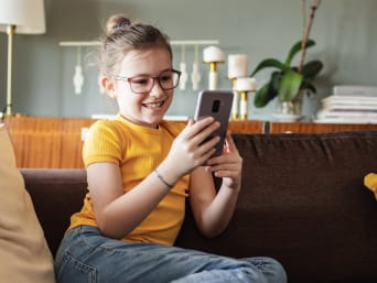 Pierwszy smartfon dla dziecka: dziewczynka cieszy się z możliwości, jakie daje jej telefon komórkowy.