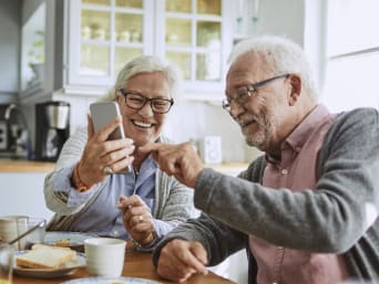 Smartphone pour sénior : un couple de personnes âgées en vidéoconférence sur téléphone portable.