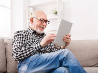 Oudere meneer gebruikt messenger service op zijn tablet.