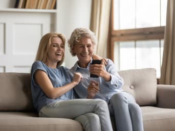 Smartphone voor senioren instellen – Moeder en dochter kijken samen op een mobiele telefoon.