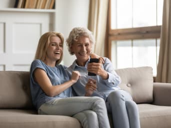 Paramétrer un smartphone pour sénior : mère et fille rient devant un téléphone portable.