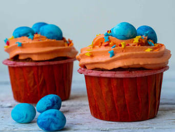 Bluey-Kindergeburtstag: Orange Muffins mit blauen Schokoeiern.