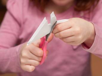 Kind bastelt Elsa-Einladungskarten für den Elsa-Kindergeburtstag.