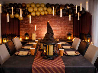 Harry Potter Geburtstag – Tisch- und Zimmerdeko in Rot und Gold mit LED-Kerzen von der Decke hängend.