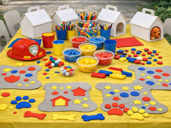 PAW-Patrol-Geburtstag: Tisch mit Hundehütten, Deko in Knochenform, Sterne, Pfotenabdrücke.