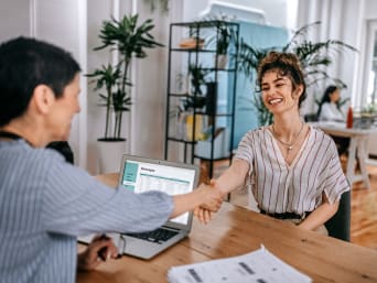 Job Modebranche: Casual gekleidete Frau stellt sich im Bewerbungsgespräch vor.