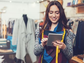 Management della moda: una donna osserva un tablet in un negozio di abbigliamento.