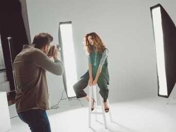 A fashion photographer doing a photoshoot with a model in a photo studio. A fashion photographer doing a photoshoot with a model in a photo studio.