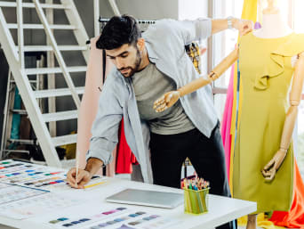 Modeontwerp studeren: ontwerper werkt aan een gele jurk.