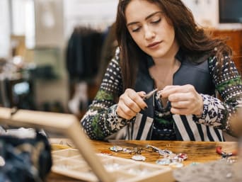 Práce v módním průmyslu: mladá žena pracuje na výrobě stříbrných šperků.
