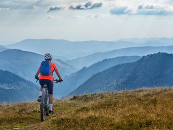 Beliebte Mountainbikestrecken in Deutschland: Frau auf einem E-Mountainbike genießt den Ausblick über den Schwarzwald.