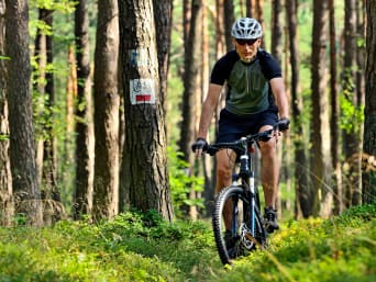 Trasy enduro – kolarz w kasku na zjeździe w lesie.