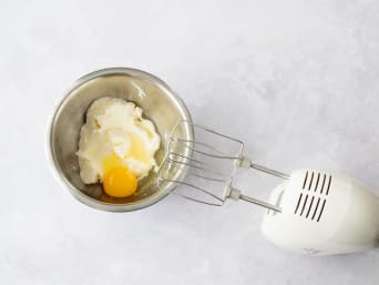 Frischkäsezuckermasse wird mit Eiern vermengt.