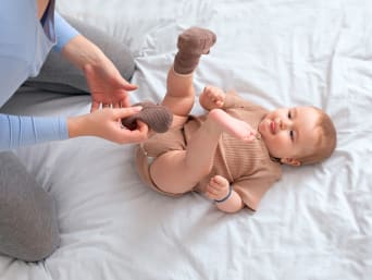 What do babies wear: a mum putting socks on her baby. 
