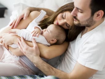 The first days with a newborn: a mum and dad cuddling with their baby.
