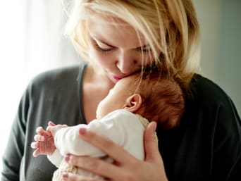 Dagelijks leven met een baby: moeder kust haar baby op het voorhoofd.