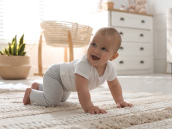 Tappe neonati: un bebè gattona su un tappeto.
