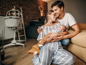 Postnatal clothes: a mum and dad cuddling with their baby.