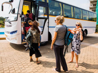 Turismo e sostenibilità: turisti in vacanza salgono su un bus di viaggio.