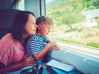 Vacanze ecologiche con bambini: una mamma e un bambino viaggiano in treno.