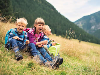 Nachhaltiger Urlaub mit Kindern: Geschwister machen Rast bei einer Wanderung.