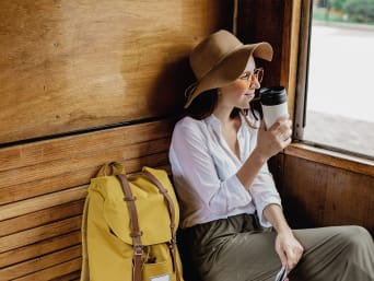 Voyager léger : une touriste dans un train avec son sac à dos minimaliste et une thermos isotherme.