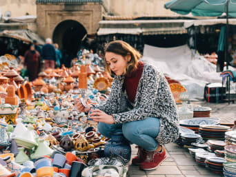 Turismo sostenibile: donna sceglie un souvenir sostenibile in un mercato in Marocco.
