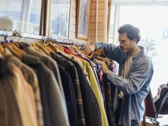Un homme essaie une veste dans une friperie à la recherche de vêtements de seconde-main. 