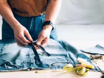 Repairing clothes: a woman is replacing a zip on her pair of jeans.