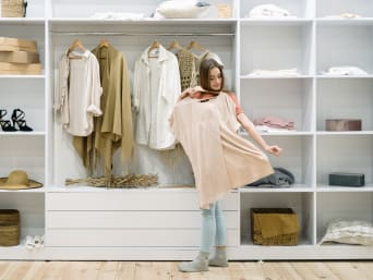 Stile di vita minimalista: una donna sceglie il suo outfit dall’armadio capsula.