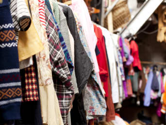 Comprar ropa usada: ropa vintage colgada de perchas en una tienda de segunda mano.