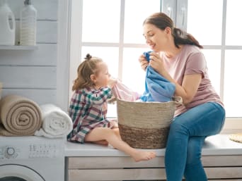 Eco-friendly ways to wash clothes: a mother and her child smelling fresh laundry.