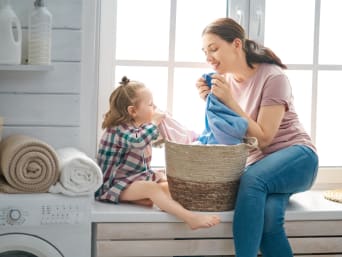 Mama z córką wąchają ubrania uprane w ekologicznych proszkach do prania.