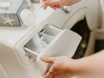 Ekologiczne pranie: kobieta oszczędnie dobiera ilość środka do prania.