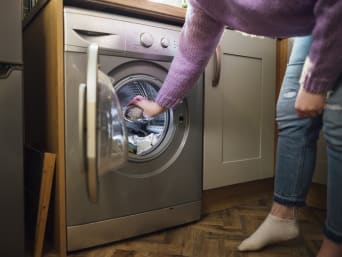 Duurzaam wassen: Vrouw doet duurzaam wasmiddel in de wasmachine.