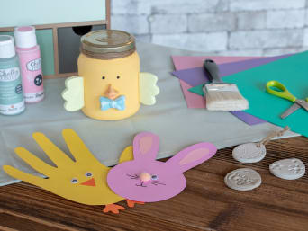 Ozdoby wielkanocne DIY dla dzieci – gotowe dekoracje i materiały do ich wykonania leżą na stole.
